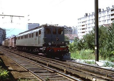 Peu après la gare de Chambéry le 24 juillet 1971, la 2CC2 3403 qui se dirige sur voie 1 vers Modane en tête d'un lourd train de messagerie va quitter la zone de transition caténaire/3ème rail qui permet de passer d'un mode de captation à l'autre sans arrêt.